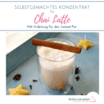 Chai Latte im Glas mit Zimtstange quar aufliegend auf hellblauem Tablett mit Nelken, Sternanis und sternförmigen Bienenwachskernen.
