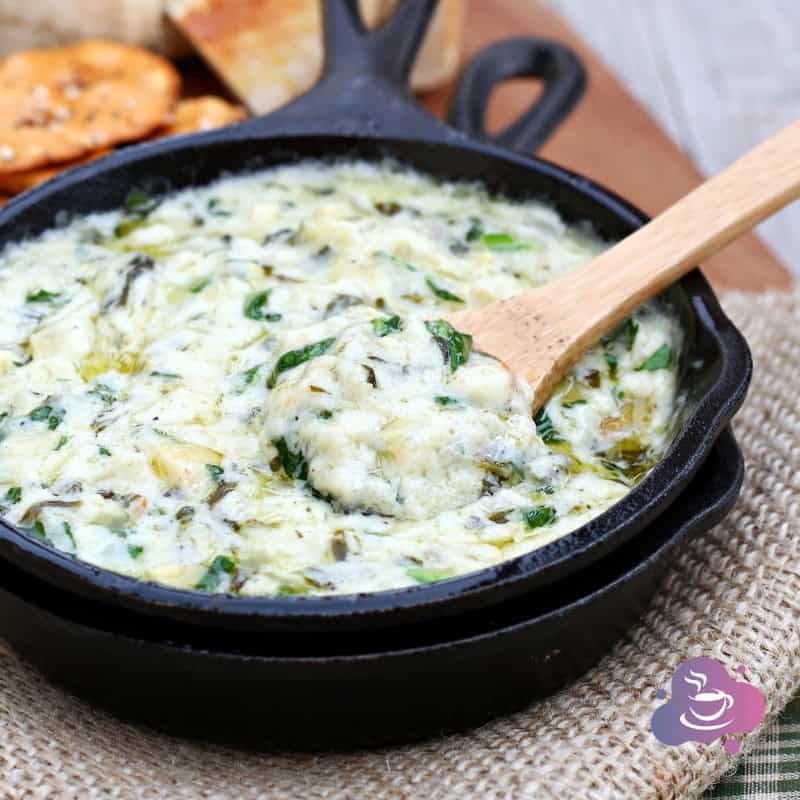 Käse-Spinat Dip mit knusprigem Brot in rustikaler Gusseisenpfanne, perfekt zum Teilen.