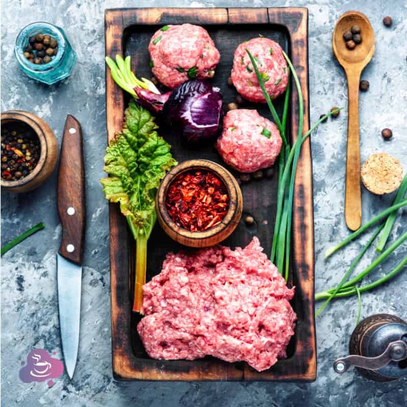 Frisches rohes Hackfleisch mit Gemüse, Kräutern und Gewürzen für die Zubereitung.
